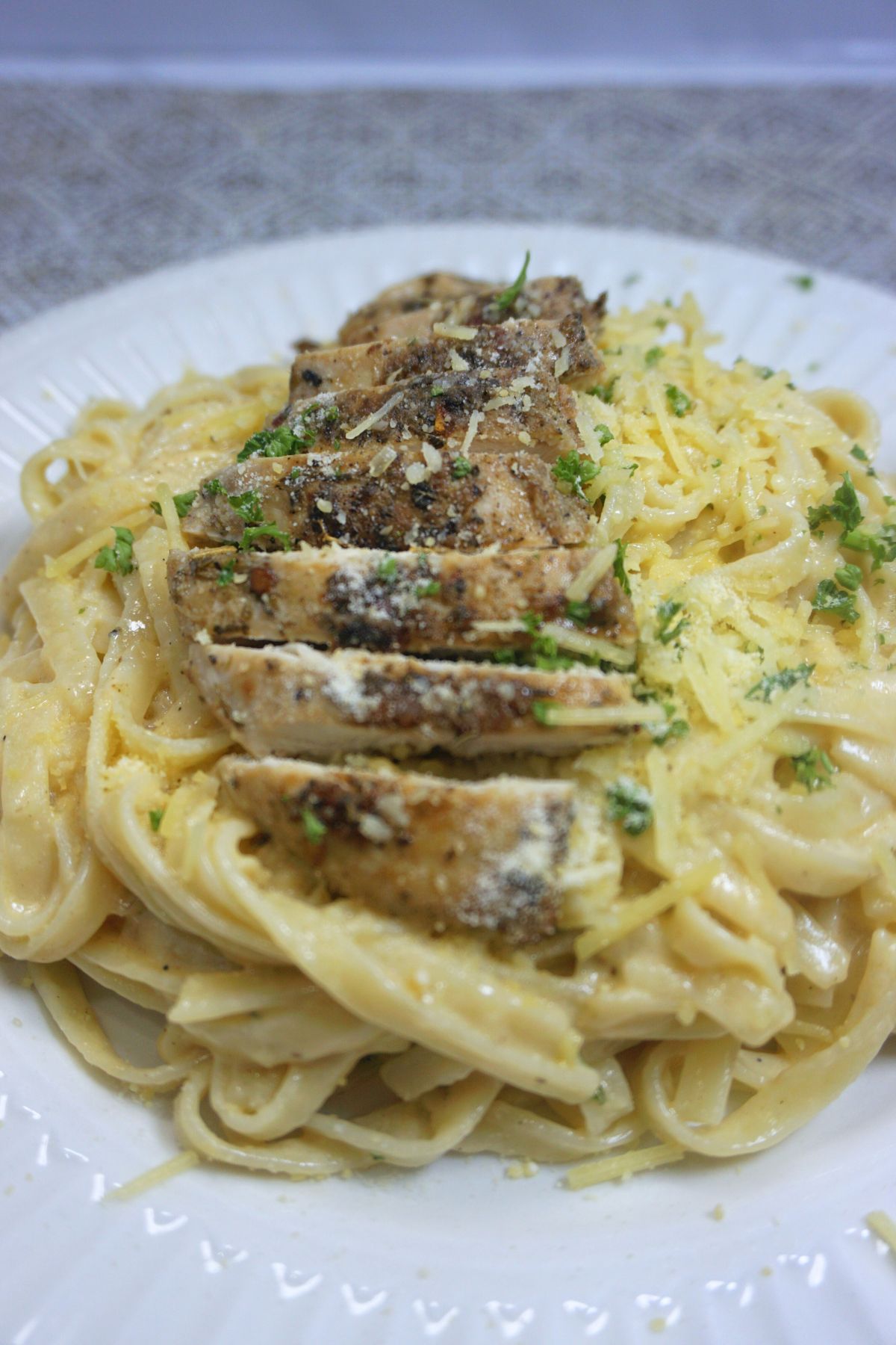 Serving for chicken alfredo with sliced chicken on top