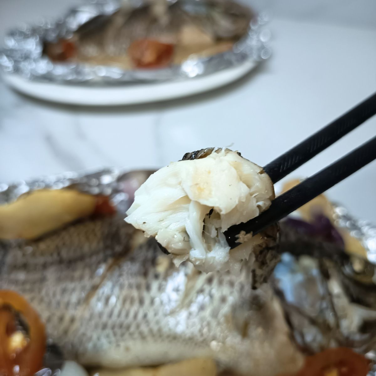 Chopsticks picking steamed tilapia meat