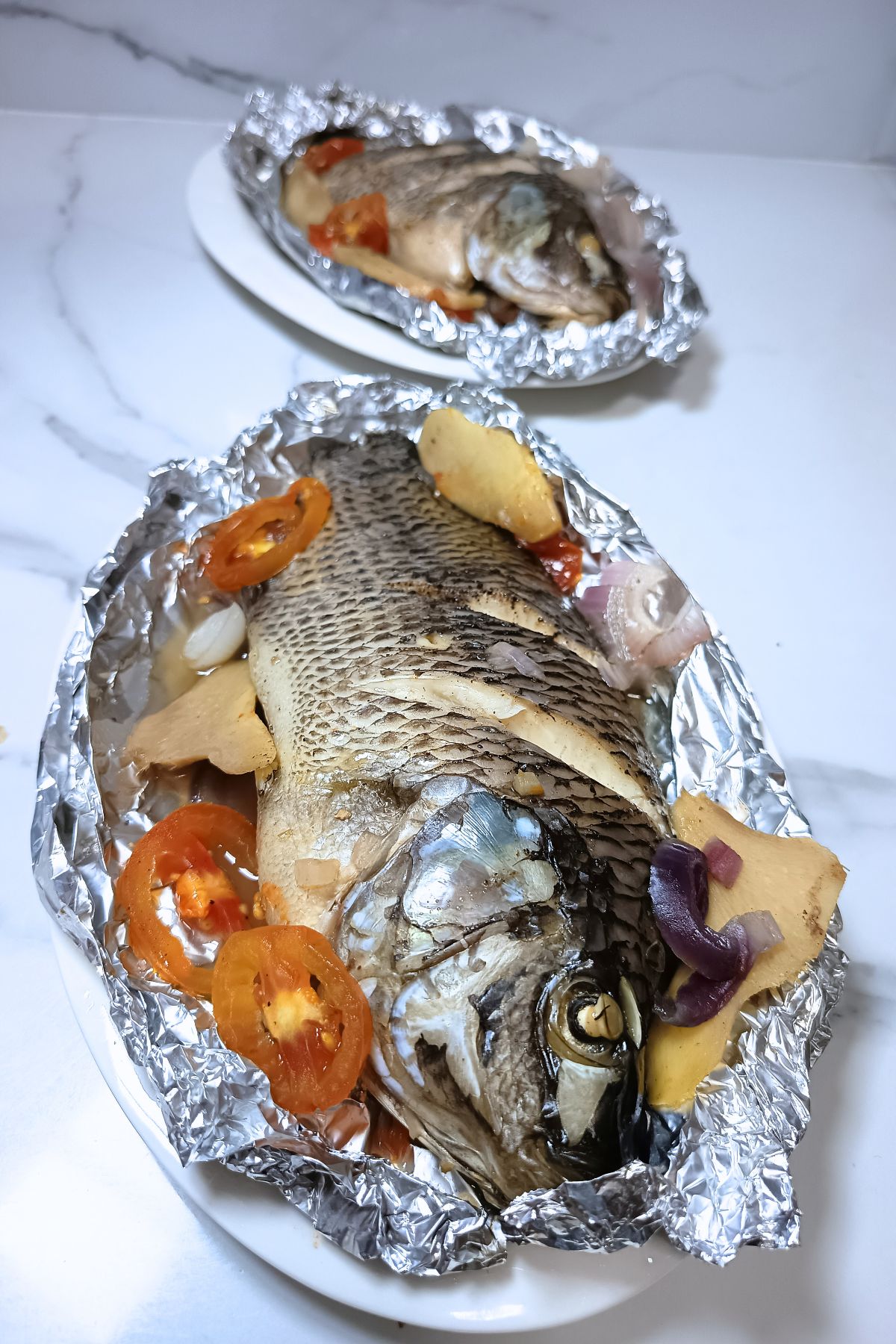 Steamed tilapia garnished with sliced tomato and ginger