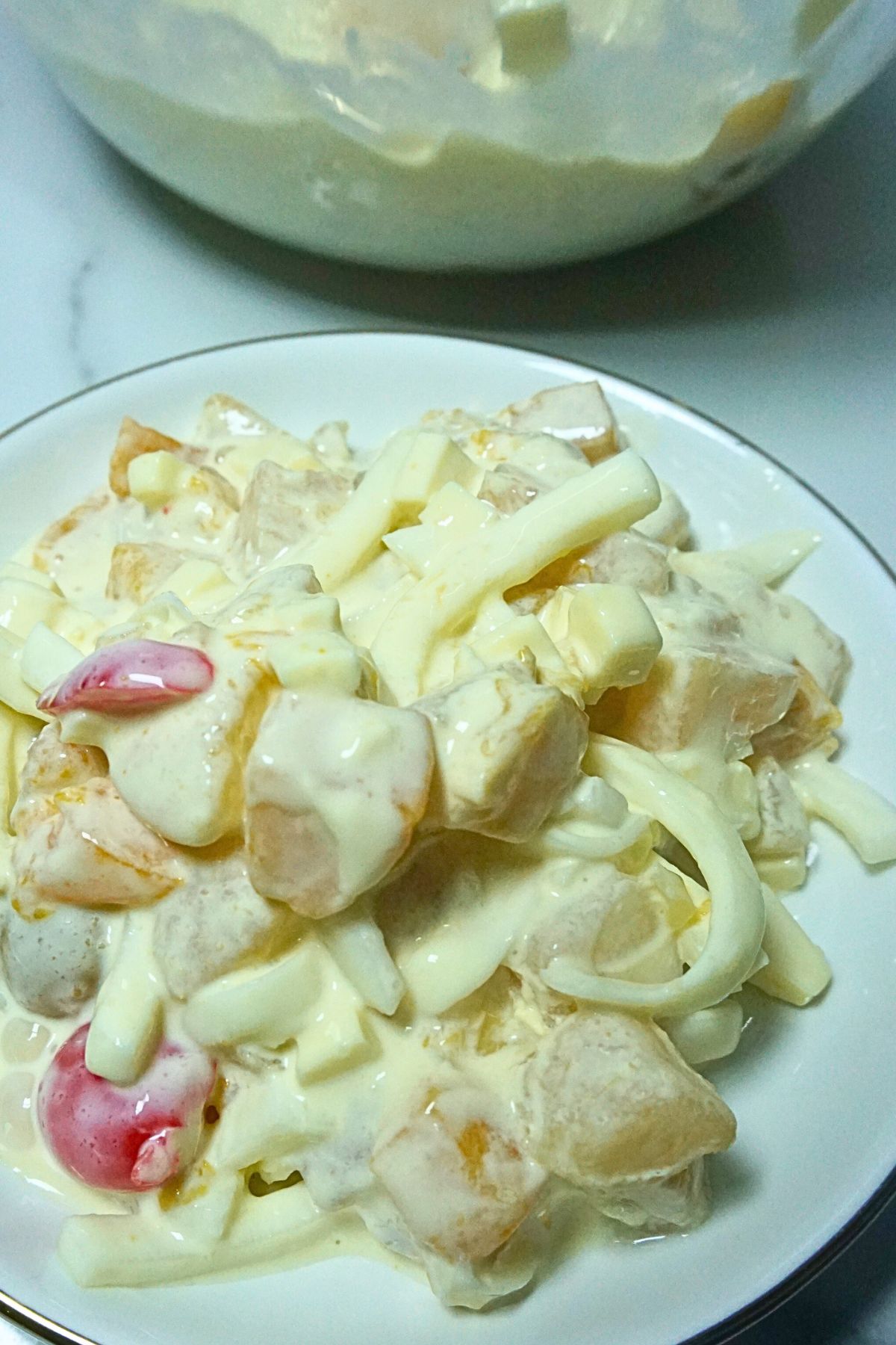 Creamy fruit cocktail salad in a plate.