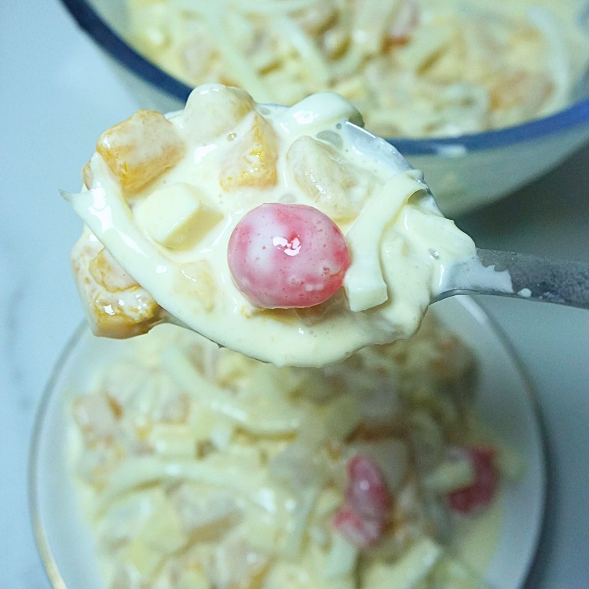 Creamy fruit salad in spoon