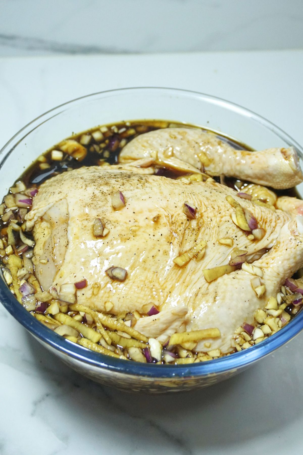 Whole Chicken marinated in a large glass bowl