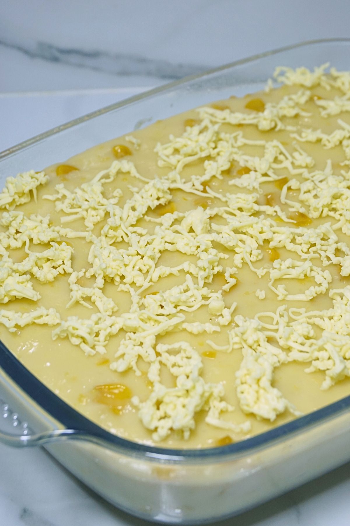 Maja blanca topped with grated cheese in a glass baking dish
