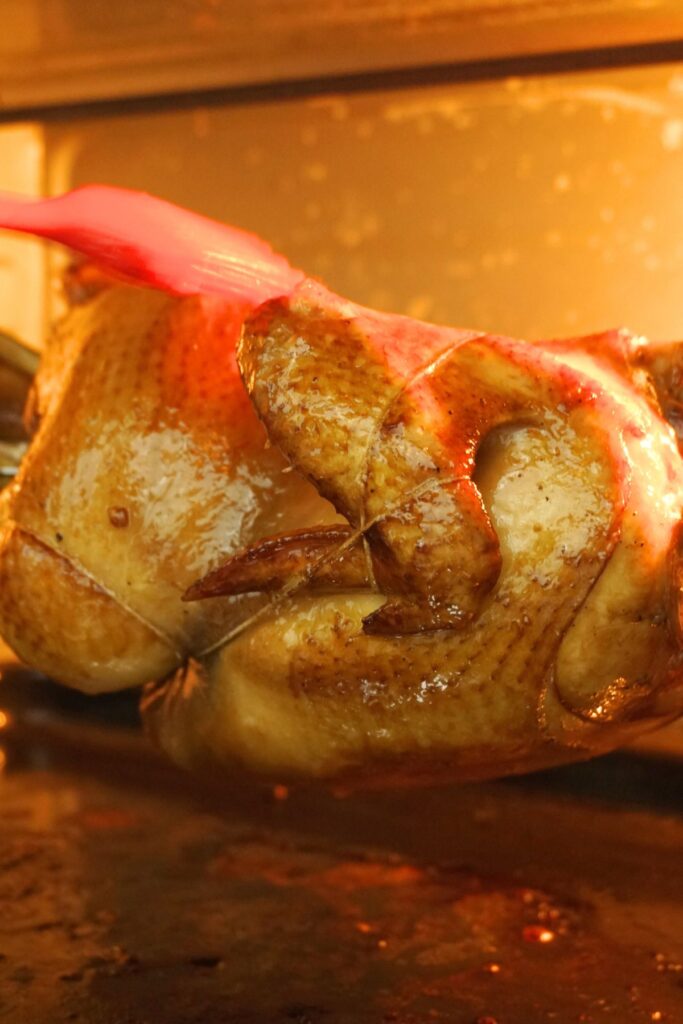 Basting roast chicken inside an oven