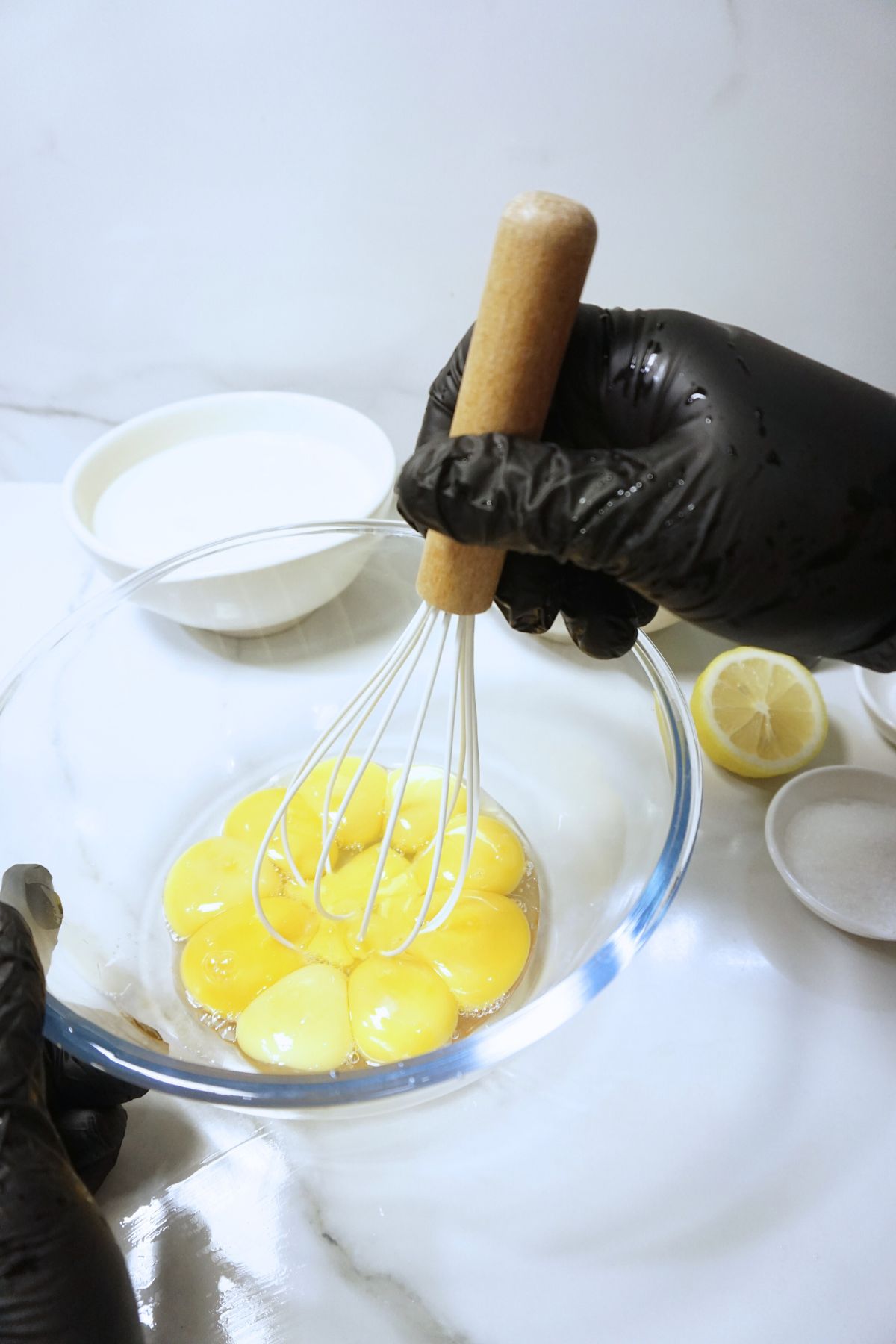 Gently whisking egg yolks in a glass bowl.