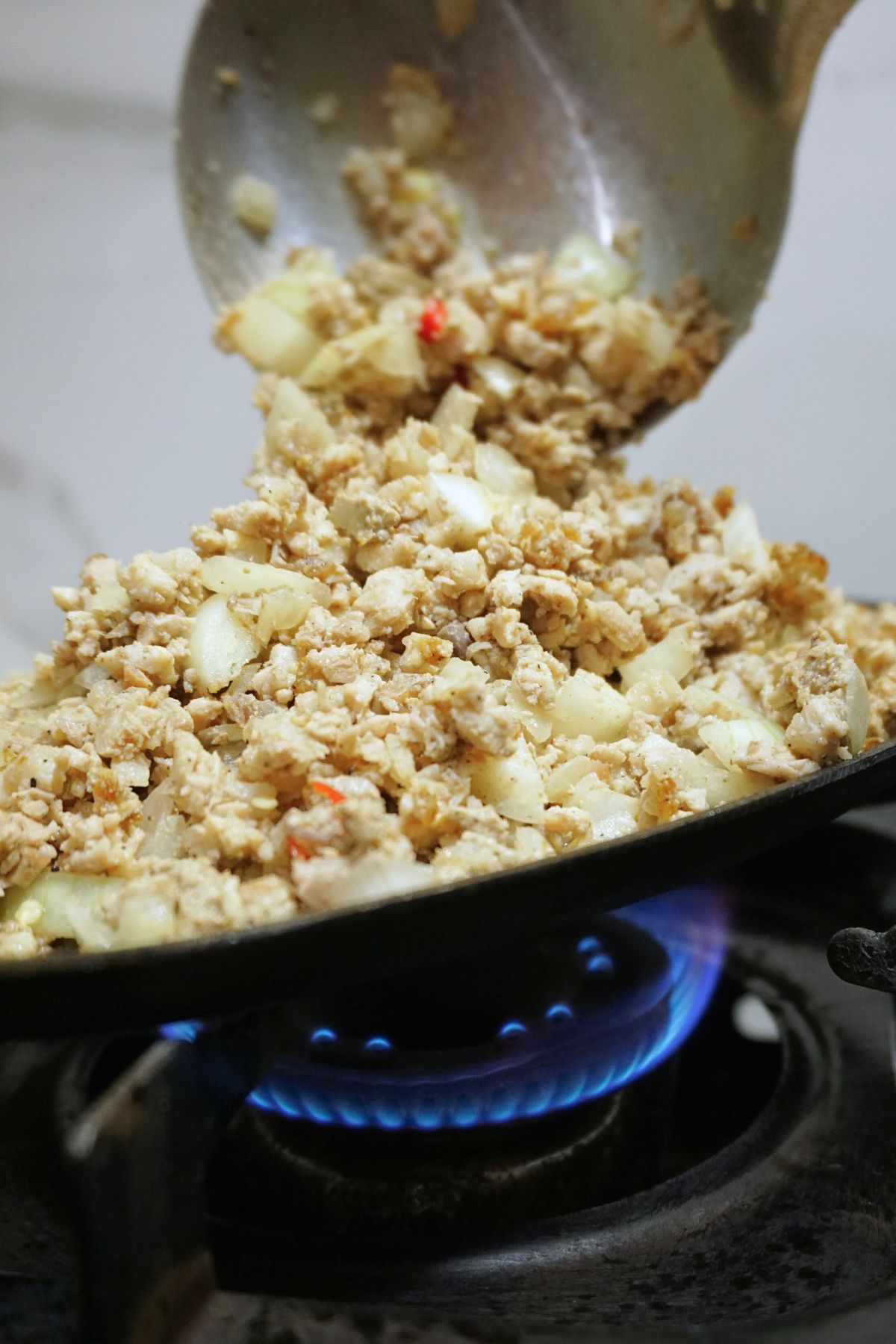 Pork sisig on a sizzling plate heated on top of stove