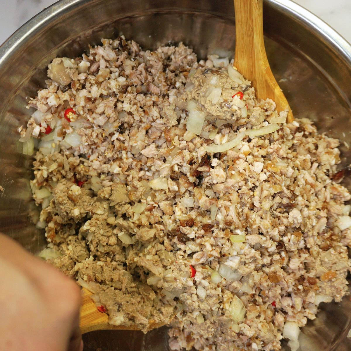 Pork sisig mixed in a metal bowl.